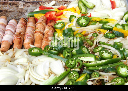 Enveloppé de bacon hot-dogs, les oignons, les jalapenos, et plusieurs variétés de poivrons grillées sur une piscine fournisseurs grill. close up. Banque D'Images