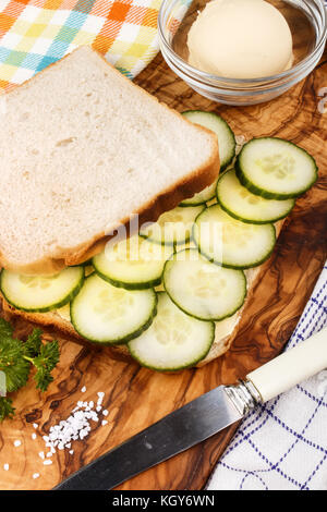 Préparer un blanc grillé sandwich avec concombre biologique sur une planche en bois Banque D'Images