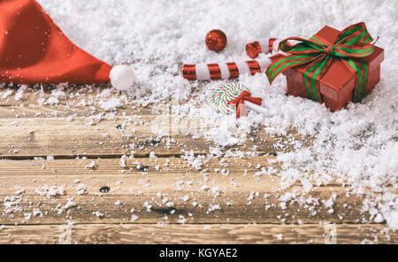 Ornements de noël et père noël hat sur fond de neige en bois Banque D'Images