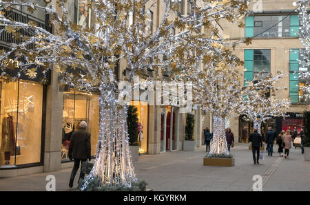 Les amateurs de shopping se promisent à Mulatrees Walk, Édimbourg, Écosse, Royaume-Uni, devant les vitrines de luxe avec décorations d'arbres de Noël illuminées Banque D'Images