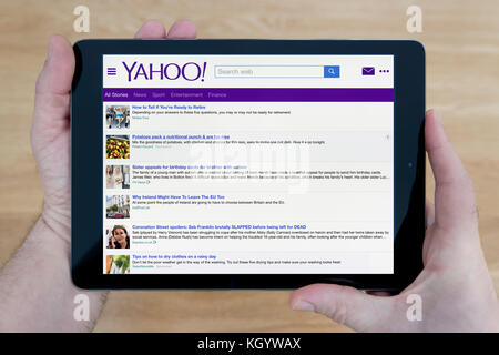 Un homme regarde le site web de Yahoo sur son iPad tablet device, tourné contre une table en bois page contexte (usage éditorial uniquement) Banque D'Images