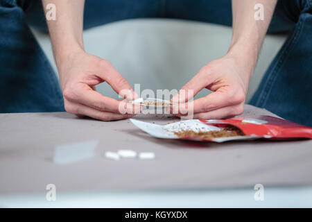 Les deux mains de l'homme rouler des cigarettes contenant du tabac Banque D'Images