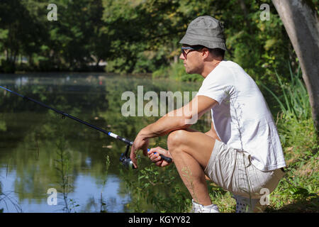 Homme avec une canne à pêche au bord du lac Banque D'Images