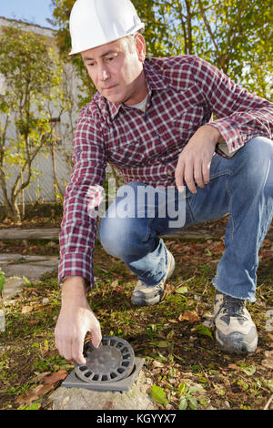 Travailleur de la construction de l'inspection de sortie de l'eau dans le jardin Banque D'Images