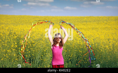 Happy little girl waving avec des rubans colorés sur terrain Banque D'Images