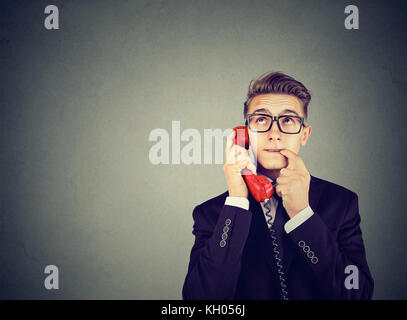 L'incompréhension et l'appel lointain. contrarié inquiets confondu man talking on a téléphone a de nombreuses questions isolé sur fond gris. Banque D'Images