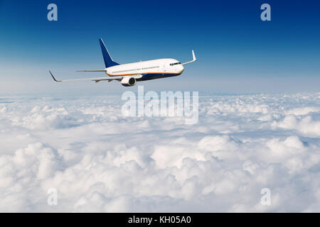 Avion volant au-dessus des nuages sur fond de ciel bleu. Banque D'Images