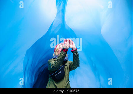 Femme de photographier à une caverne de glace dans la région de Fox Glacier, île du Sud, Nouvelle-Zélande Banque D'Images