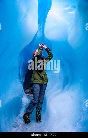 Femme de photographier à une caverne de glace dans la région de Fox Glacier, île du Sud, Nouvelle-Zélande Banque D'Images