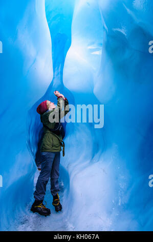 Femme de photographier à une caverne de glace dans la région de Fox Glacier, île du Sud, Nouvelle-Zélande Banque D'Images