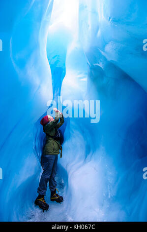 Femme de photographier à une caverne de glace dans la région de Fox Glacier, île du Sud, Nouvelle-Zélande Banque D'Images