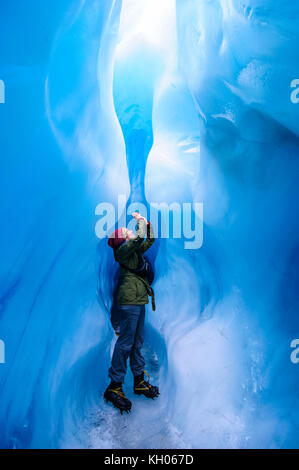 Femme de photographier à une caverne de glace dans la région de Fox Glacier, île du Sud, Nouvelle-Zélande Banque D'Images