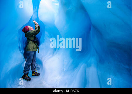 Femme de photographier à une caverne de glace dans la région de Fox Glacier, île du Sud, Nouvelle-Zélande Banque D'Images