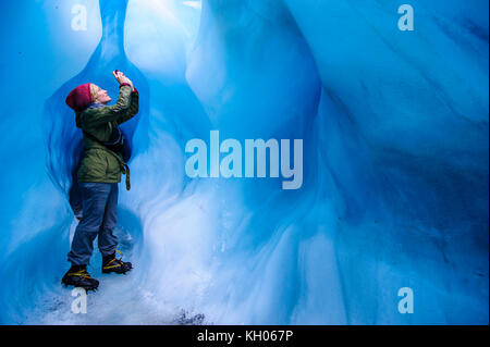 Femme de photographier à une caverne de glace dans la région de Fox Glacier, île du Sud, Nouvelle-Zélande Banque D'Images