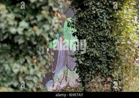 Partie de fresque de rue avec personnage Star Wars Yoda vu de derrière les arbres de lierre sur le côté de la route dans l'Est de Londres. Banque D'Images