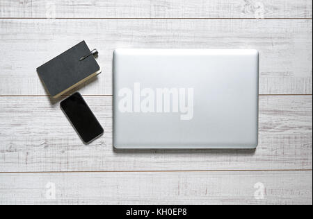 Vue d'une table en bois avec un ordinateur portable, mobile, portable et d'un stylo sur elle Banque D'Images