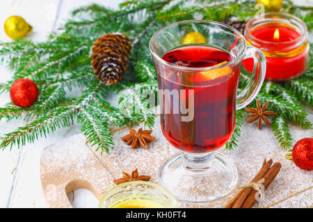 Nouvelle année, le vin chaud dans un verre sur l'arrière-plan de brindilles, de bougies et de guirlandes Banque D'Images