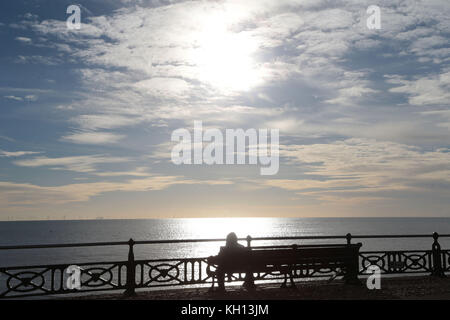 Hove, Sussex Coast. 13th novembre 2017. Météo au Royaume-Uni : une journée d'hiver sur le front de mer de Hove qui annonce l'arrivée de la première prise froide de l'année. Une marchette enveloppée s'arrête pour admirer le parc de Rampion au large de la côte du Sussex, la centrale de £1,3 milliards sera l'une des plus grandes d'Europe. Météo crédit photo: Nigel Bowles/Alay Live News Banque D'Images