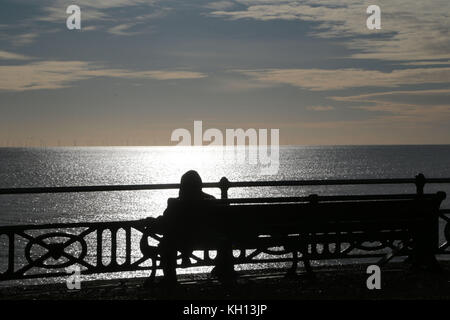 Hove, Sussex Coast. 13th novembre 2017. Météo au Royaume-Uni : une journée d'hiver sur le front de mer de Hove qui annonce l'arrivée de la première prise froide de l'année. Une marchette enveloppée s'arrête pour admirer le parc de Rampion au large de la côte du Sussex, la centrale de £1,3 milliards sera l'une des plus grandes d'Europe. Météo crédit photo: Nigel Bowles/Alay Live News Banque D'Images