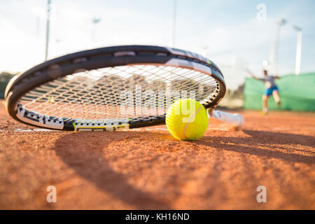 Close-up raquette de tennis et la balle placée sur le sol de la cour tout en player hitting ball. Banque D'Images