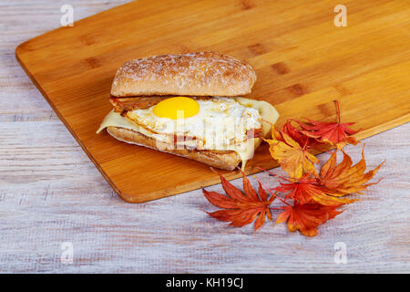 Sandwich avec du bacon et oeuf de poule sur un fond de bois. Banque D'Images