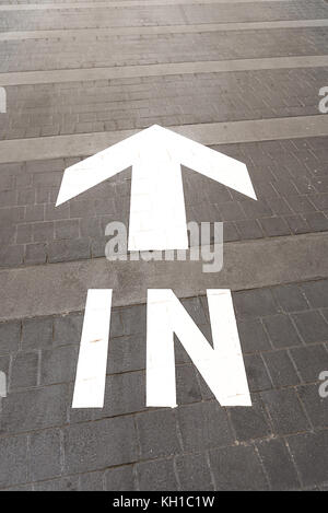 Une lumière blanche flèche directionnelle et le mot 'in' peint sur une route chemin entrée. Banque D'Images