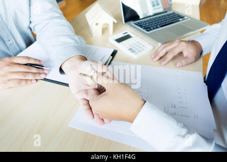 Agent immobilier en cause assis dans un bureau 24 Remise des clés de la maison avec le client après la signature du contrat. Banque D'Images