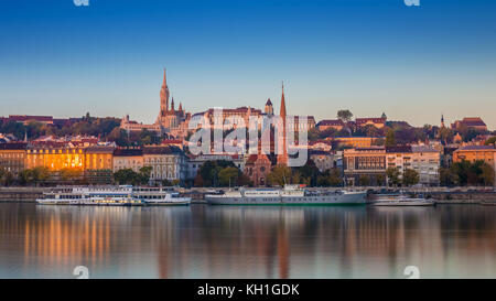 Budapest, Hongrie - vue sur le lever du soleil sur Buda Side de Budapest avec le château de Buda, l'église Saint-Matthias et la Bastion des pêcheurs avec de vieux bateaux sur Rive Banque D'Images