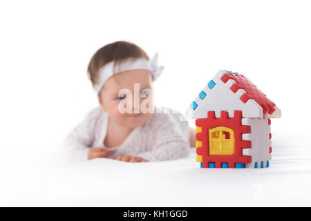 Portrait of baby girl et plastique jouet maison isolé sur fond blanc Banque D'Images