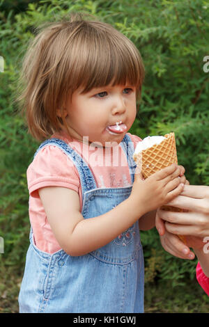 Cute baby girl mangent des glaces de l'été avec mis out tongue Banque D'Images