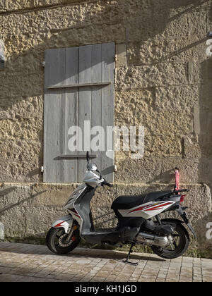 SAINTES, FRANCE - 09 SEPTEMBRE 2017 : scooter stationné à l'extérieur d'une maison avec des volets en bois Banque D'Images