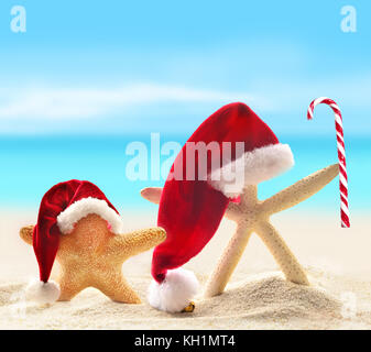 Dans l'étoile rouge santa hat sur plage de sable fin et des bonbons Banque D'Images