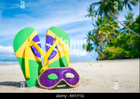 Drapeau Brésil tongs avec masque de carnaval brésilien de palmiers sur la plage. Banque D'Images