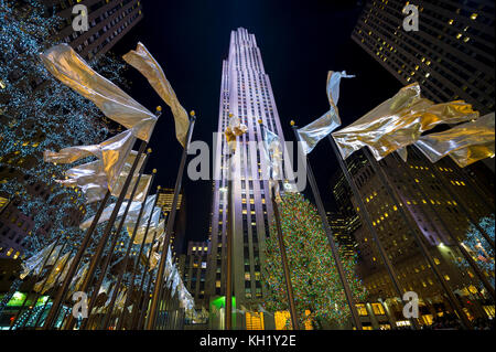 NEW YORK - 21 DÉCEMBRE 2016 : des drapeaux de vacances flottent autour de la place centrale en face de l'arbre de Noël du Rockefeller Center, l'un des plus hauts de la ville Banque D'Images