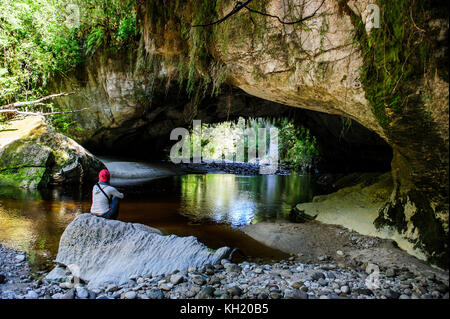 Woman la magnifique porte de la moria arch dans le bassin, oparara karamea, île du Sud, Nouvelle-Zélande Banque D'Images