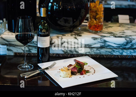 Un plat de côtelette d'agneau accompagné d'une bouteille et verre de vin rouge Banque D'Images