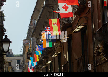 Drapeaux de divers pays du monde sont accrochés sur l'un des bâtiments de l'Italie et sont éclairés par l'éclairage du soleil Banque D'Images