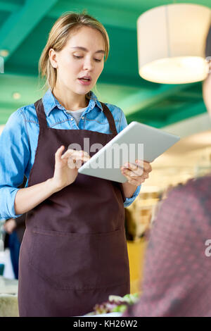 Portrait of young cafe waitress taking order tablier port du client using digital tablet Banque D'Images