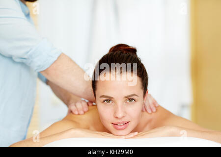 Jeune femme caucasienne couchée dans un salon de spa pendant que masseur fait massage sur son dos Banque D'Images