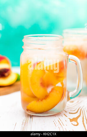 Limonade glacée faite maison avec pêches mûres. fresh peach thé glacé dans un pot Mason Banque D'Images