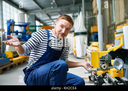 Portrait de confus de réparateur de surprise en essayant de fixer l'unité machine à l'usine Banque D'Images