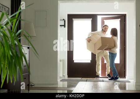 Heureux jeune couple portant des boîtes en carton ouvrant la porte à l'intérieur de la maison propre moderne, excité les propriétaires de propriété familiale mariée emménageant dans le nouveau h Banque D'Images