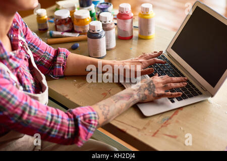 Vue rapprochée de jeune femme à l'aide d'un ordinateur portable moderne, l'accent sur les femmes tatouées hands typing Banque D'Images