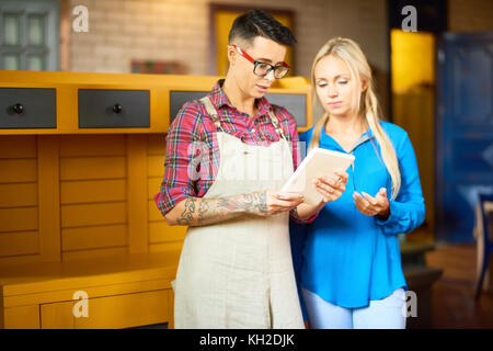 Portrait de deux jeunes femmes créatifs appréciant travailler ensemble en studio art à l'aide de tablette numérique lors de la planification de projet suivant Banque D'Images