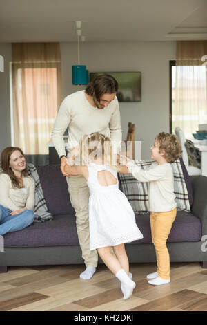 Jeune père jouant avec son fils et sa fille à la maison, heureux mari papa aime passer du temps avec les enfants tout en femme mère assise sur un canapé, peu d'enfants Banque D'Images