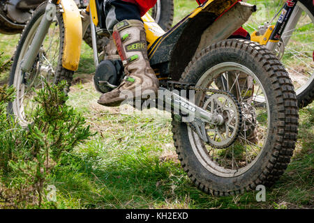 Gros plan de la roue arrière du vélo de motocross en action avec des bottes hors route sur un sentier de motocross à Brittas, Wicklow, Irlande Banque D'Images
