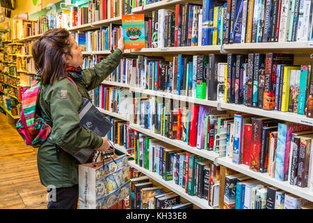 Une femme livre ses achats dans une célèbre boutique caritative Oxfam High Street, Book shopping Londres Angleterre Royaume-Uni Banque D'Images
