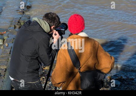 Deux jeunes photographes dans une conversation animée sur l'estran Thames, London, UK. Banque D'Images