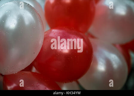 Des ballons blancs et rouges avec des gouttes de pluie Banque D'Images