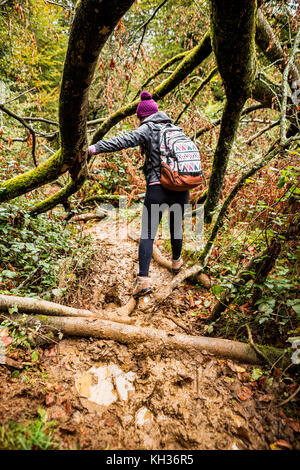 Une jeune femme traversant un sentier de forêt boueux Banque D'Images